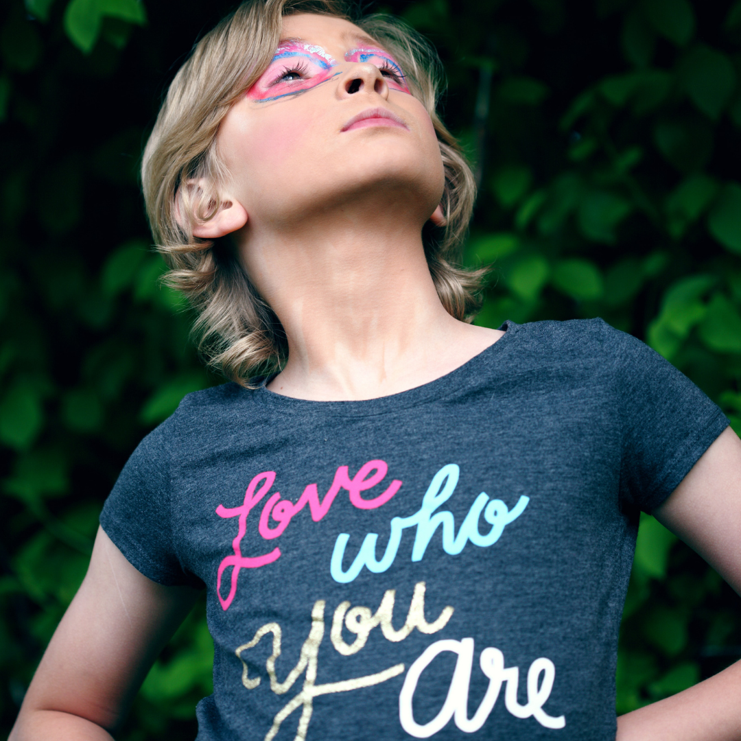 a child with a shirt that says 'love who you are' looking proud
