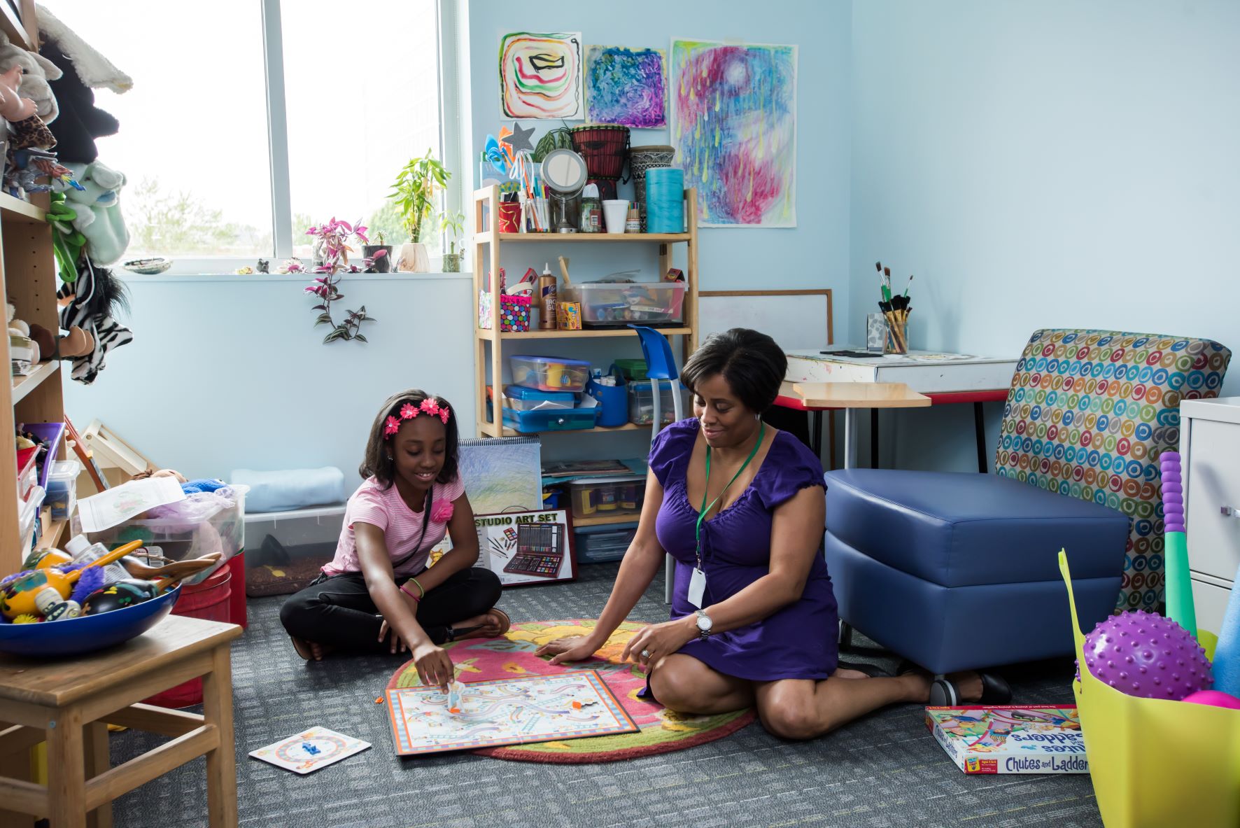 a girl and a woman playing a board game in a room full of toys